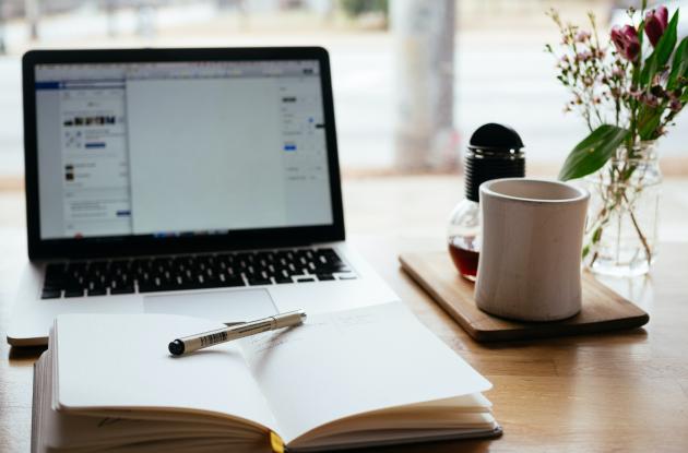 Laptop with a book and coffee in front