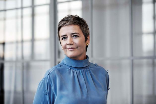 Fotografi af Margrethe Vestager foran glasbygning